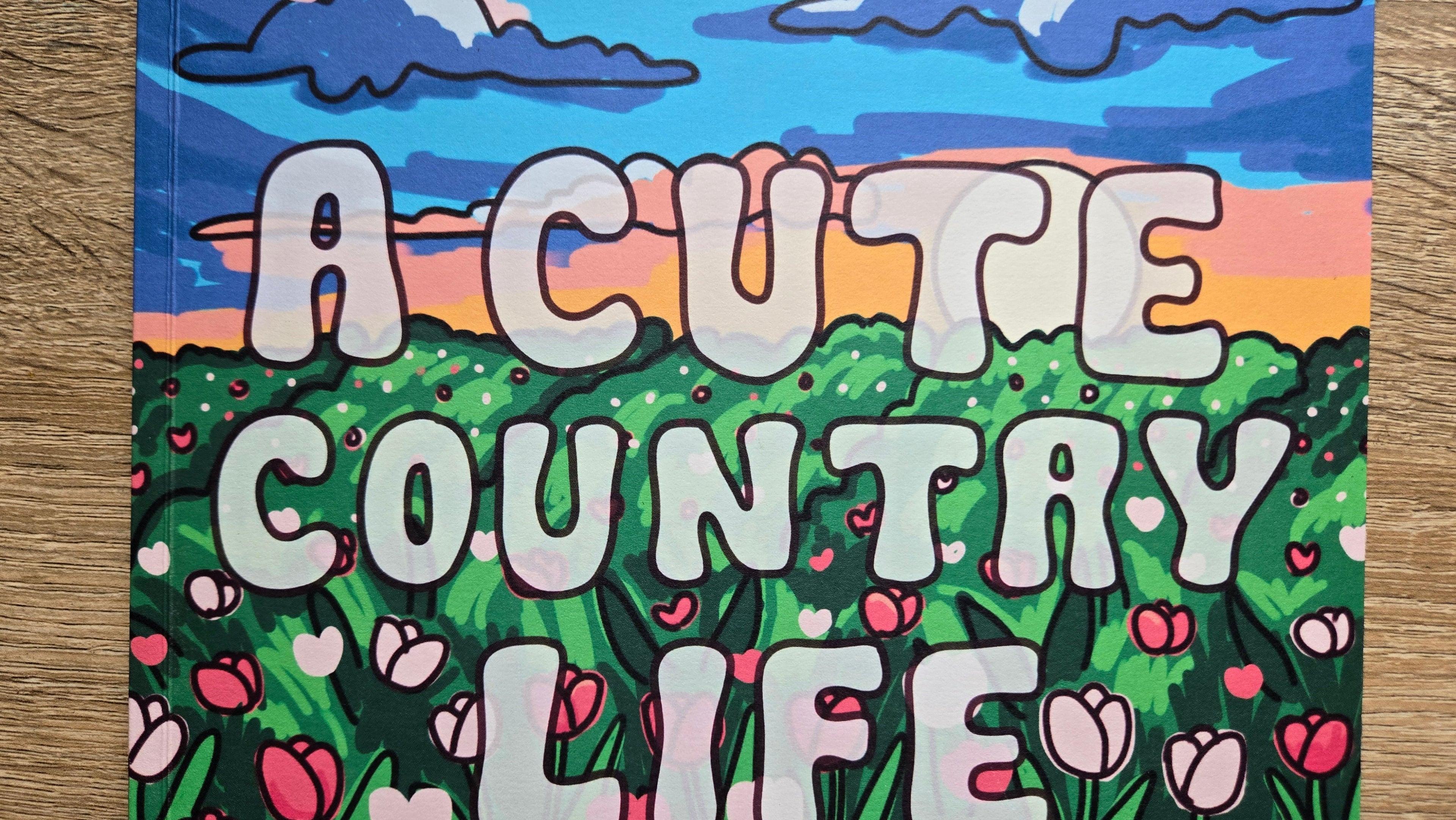 Poster with 'A Cute Country Life' text and landscape design on a wooden surface